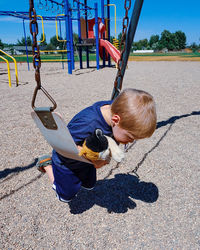 Boy playing on swing at playground