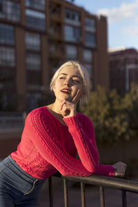 Portrait of young woman standing against building