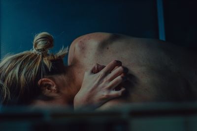 Close-up of shirtless woman scratching her back