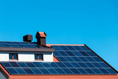 Low angle view of house roof against blue sky