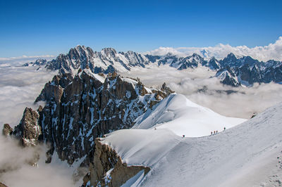 Snowy peaks and mountaineers in a sunny day at the aiguille du midi, near chamonix, france.