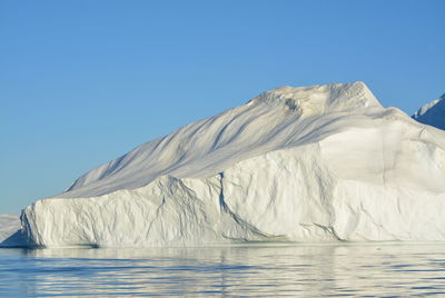 View of majestic iceberg in sea against sky