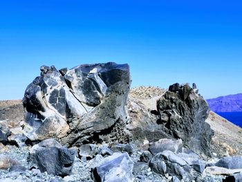 Rocks in sea against clear blue sky