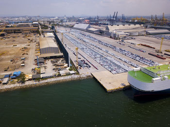 Aerial logistics commercial vehicles waiting to be load on to a car carrier ship at dockyard