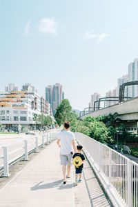 People on street amidst buildings in city against sky
