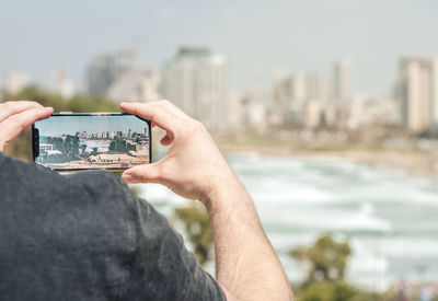 Midsection of man using mobile phone in city