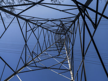 Low angle view of electricity pylon against clear blue sky