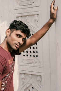 Portrait of young man standing by wall