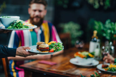 Cropped hand of waiter keeping food on table in restaurant