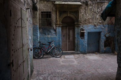 Bicycle parked on footpath against old house