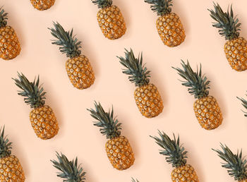 A bright pattern of many pineapples on a trendy soft beige pink background. tropical fruit 