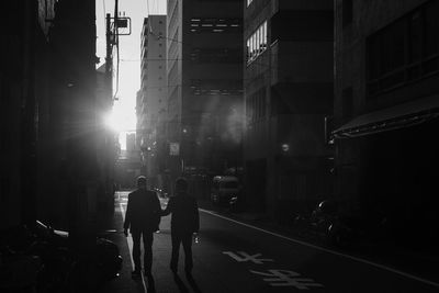 Rear view of people walking on street in city