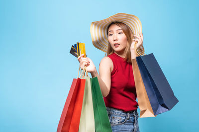 Young woman holding umbrella against blue background