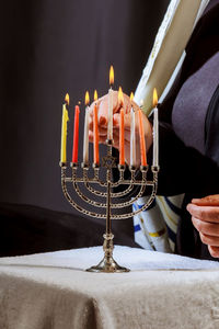 Midsection of person lighting candles on stick holder