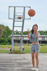 Full length of a young woman playing basketball