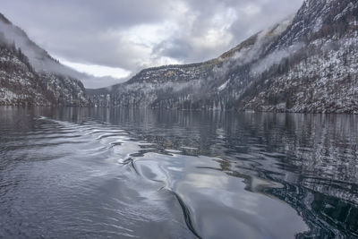 Scenic view of lake by snowcapped mountains against sky