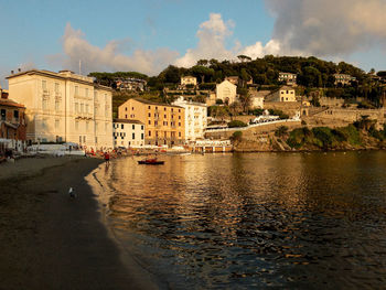 Buildings by river against sky in city