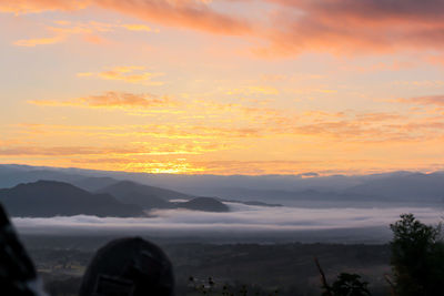 Scenic view of silhouette mountains against orange sky