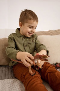 Little and cute caucasian boy playing with dinosaurs at home.