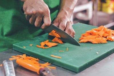 Close-up of hand holding leaf on cutting board