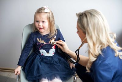 Pediatrician examining cute girl in medical clinic