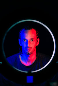 Portrait of young man wearing mask against black background