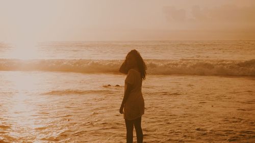 Woman standing at beach during sunset
