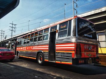 Red car on street in city against sky
