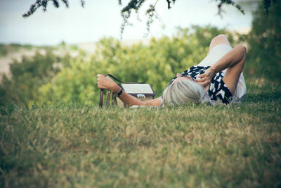 Rear view of senior woman lying on grass in field