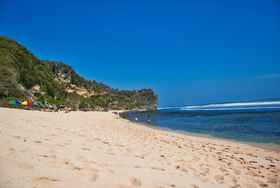 Scenic view of beach against clear blue sky