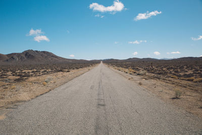 Road amidst desert against sky