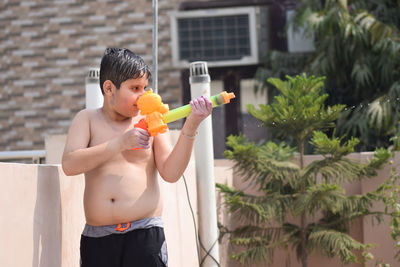 Shirtless boy playing with squirt gun during holi