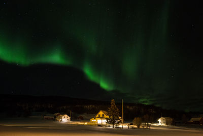 Aurora borealis in sky over illuminated houses
