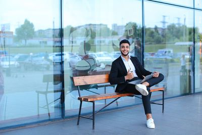 Businessman using digital tablet while sitting on bench outdoors