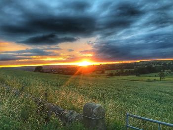 Scenic view of field against dramatic sky