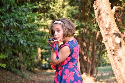 Portrait of cute girl blowing kiss at public park