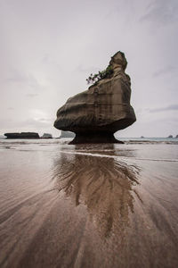 Rock formation on beach against sky