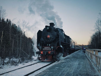 Train on railroad tracks against sky during winter