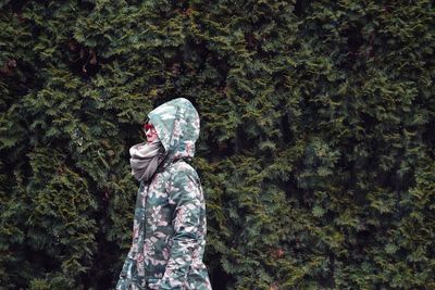 Side view of young standing against in forest