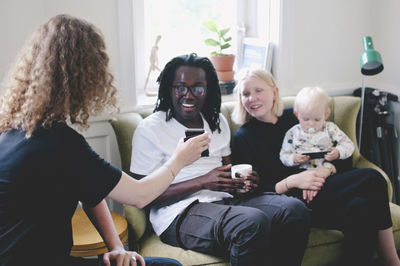 Young businesswoman showing mobile phone to colleagues in creative office