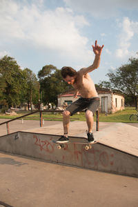 Full length of shirtless boy jumping against sky