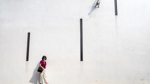 Woman standing against white wall