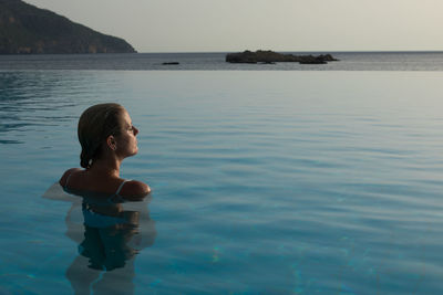 Woman in swimming pool against sea