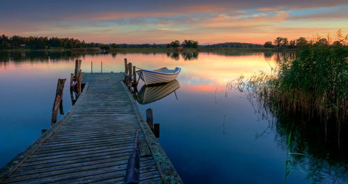 Pier on lake against sky during sunset