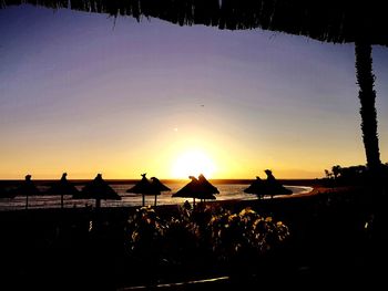 Silhouette people on beach against sky during sunset