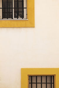 Full frame shot of windows with yellow frane on white wall of building