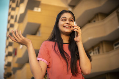 Young woman looking away against wall