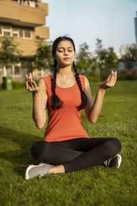 Portrait of young woman exercising on field