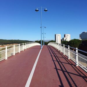 Street lights on bridge against clear blue sky