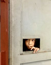 Portrait of boy peeking through window